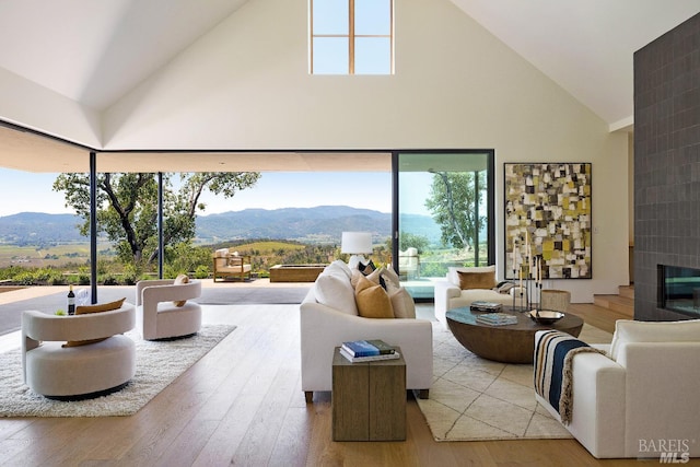living area with high vaulted ceiling, wood finished floors, and a mountain view