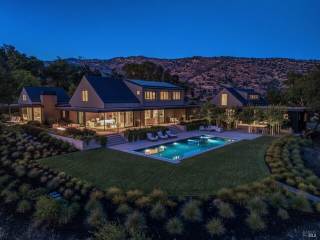 rear view of house featuring an outdoor pool, a mountain view, a yard, and a patio area