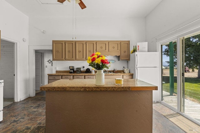 kitchen with ceiling fan, white fridge, dark tile flooring, high vaulted ceiling, and a center island