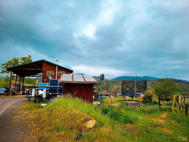 exterior space with a mountain view, solar panels, and a trampoline