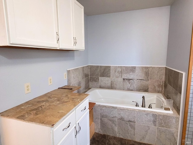 bathroom featuring tile patterned flooring, vanity, and tiled bath