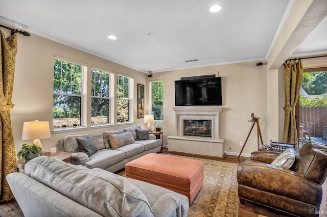 living room with ornamental molding, a tiled fireplace, and hardwood / wood-style floors