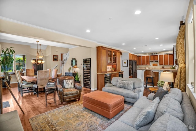 living room with ornamental molding, a chandelier, and light wood-type flooring