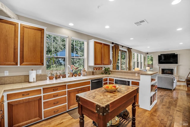 kitchen featuring black dishwasher, tile countertops, sink, and light hardwood / wood-style flooring