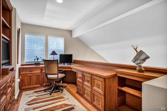 office space with vaulted ceiling with beams, built in desk, and light hardwood / wood-style flooring