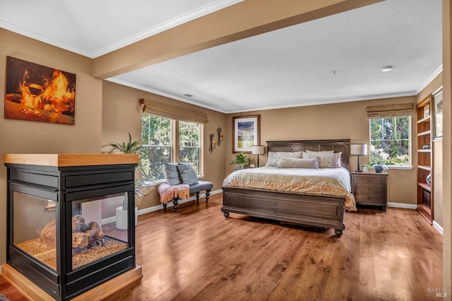 bedroom featuring ornamental molding, hardwood / wood-style floors, a multi sided fireplace, and multiple windows