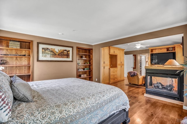 bedroom with crown molding, ceiling fan, wood-type flooring, and a multi sided fireplace