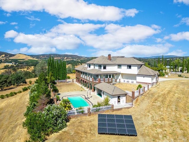 back of house with a yard, a mountain view, a patio, and solar panels