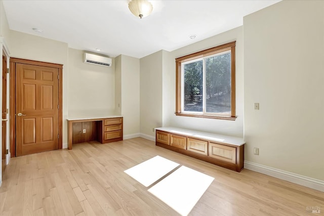 unfurnished bedroom featuring light hardwood / wood-style floors and a wall unit AC