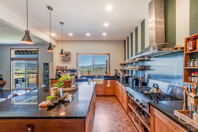 kitchen featuring hanging light fixtures, tile flooring, dark stone countertops, and wall chimney exhaust hood