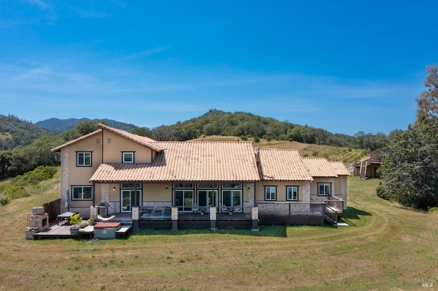 rear view of property featuring a wooden deck and a lawn