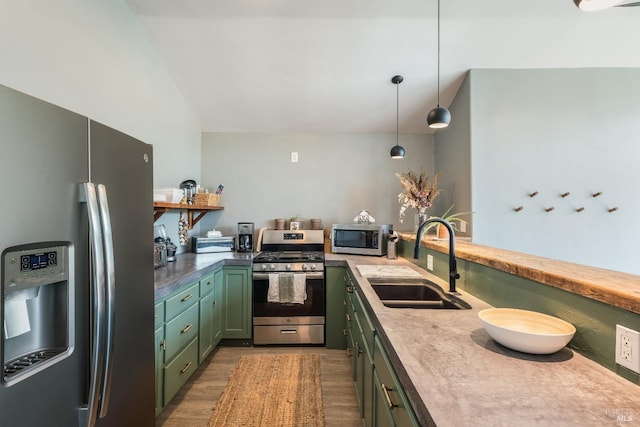 kitchen with pendant lighting, green cabinets, appliances with stainless steel finishes, sink, and dark hardwood / wood-style flooring