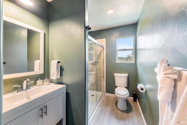 bathroom featuring hardwood / wood-style floors, toilet, a shower with shower door, and vanity with extensive cabinet space