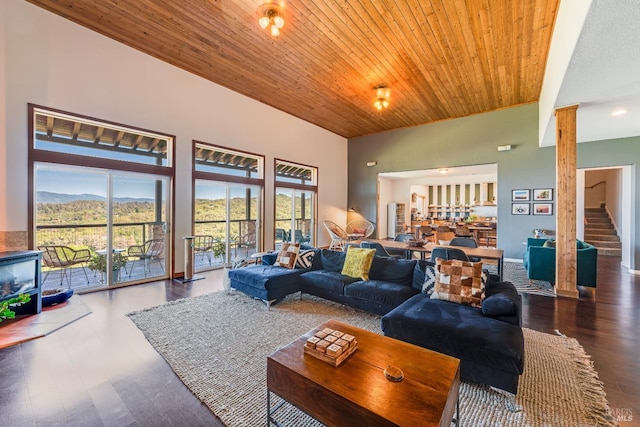 living room featuring a high ceiling, decorative columns, dark hardwood / wood-style floors, and wooden ceiling