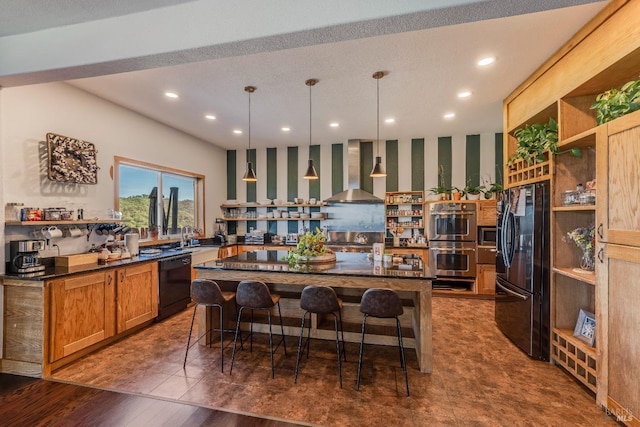 kitchen with a kitchen island, hanging light fixtures, black appliances, wall chimney exhaust hood, and a kitchen bar