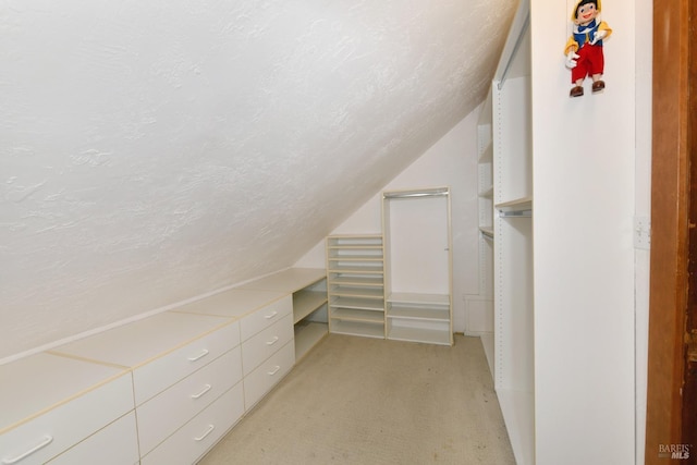 walk in closet featuring light carpet and vaulted ceiling