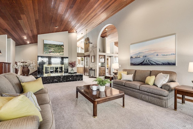 living room with light colored carpet, a premium fireplace, a towering ceiling, and wood ceiling