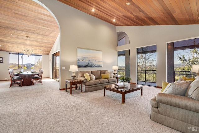 carpeted living room with high vaulted ceiling, a chandelier, and wooden ceiling