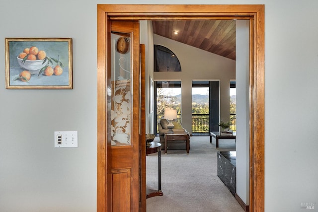 hallway featuring carpet flooring, wood ceiling, and lofted ceiling