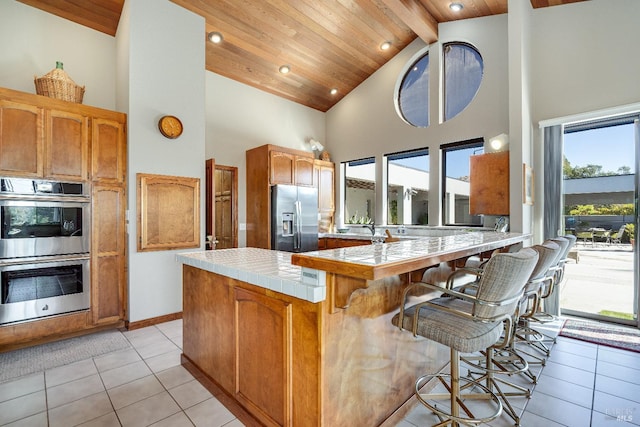 kitchen featuring high vaulted ceiling, wood ceiling, light tile flooring, and appliances with stainless steel finishes