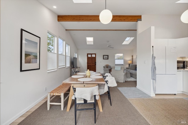 dining space with ceiling fan, vaulted ceiling with beams, and light hardwood / wood-style floors