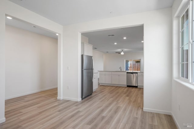 kitchen with white cabinetry, ceiling fan, appliances with stainless steel finishes, sink, and light hardwood / wood-style flooring