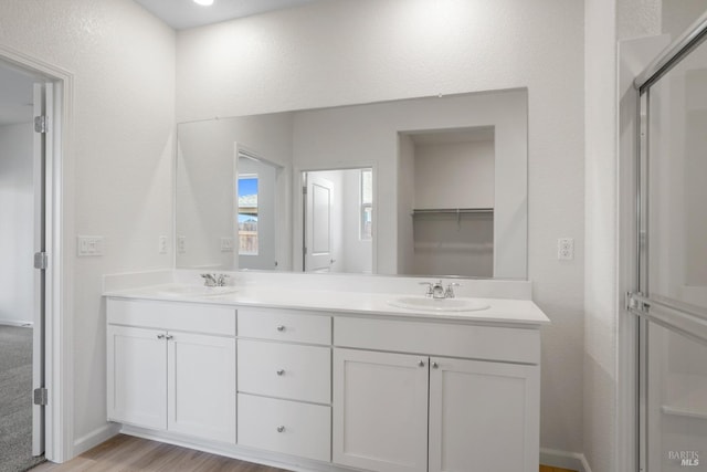 bathroom featuring oversized vanity, dual sinks, and hardwood / wood-style flooring