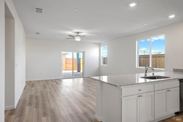 kitchen with a healthy amount of sunlight, ceiling fan, white cabinetry, and sink