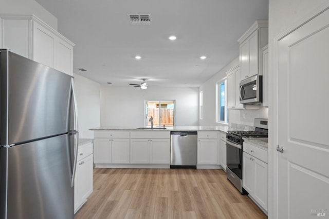 kitchen with white cabinetry, stainless steel appliances, ceiling fan, and light hardwood / wood-style flooring