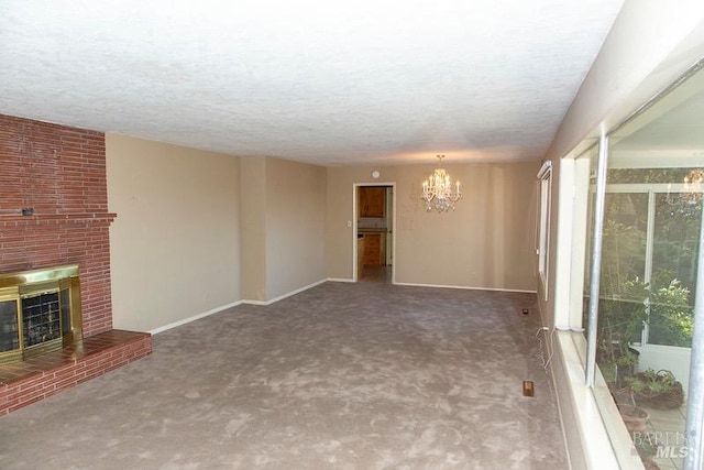 unfurnished living room featuring a brick fireplace, carpet, brick wall, and an inviting chandelier