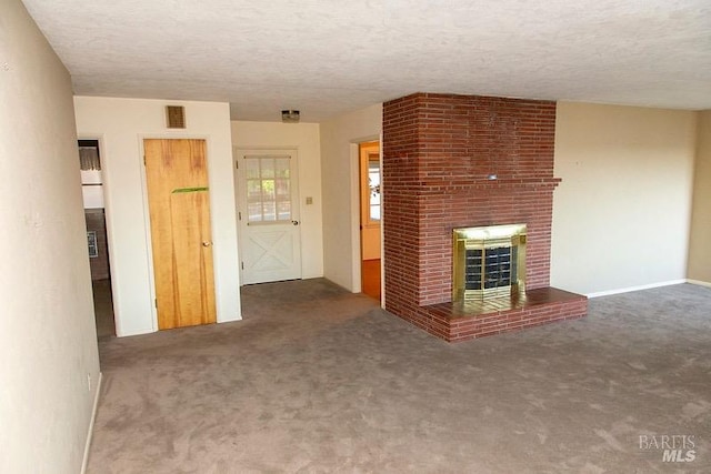 unfurnished living room with carpet flooring, brick wall, a fireplace, and a textured ceiling