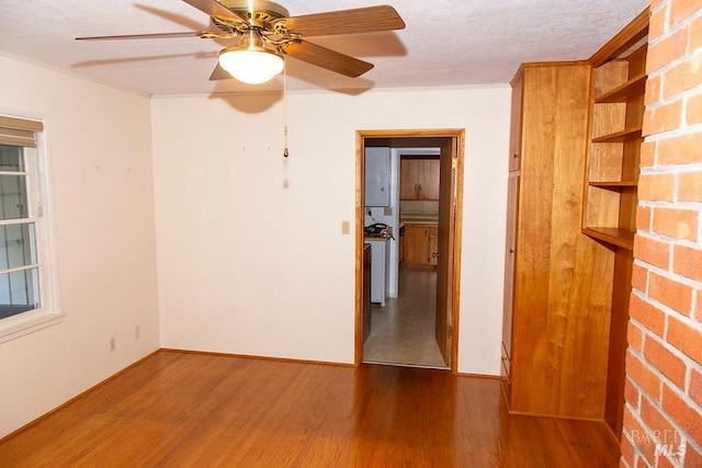 unfurnished room featuring brick wall, a textured ceiling, ceiling fan, and hardwood / wood-style floors