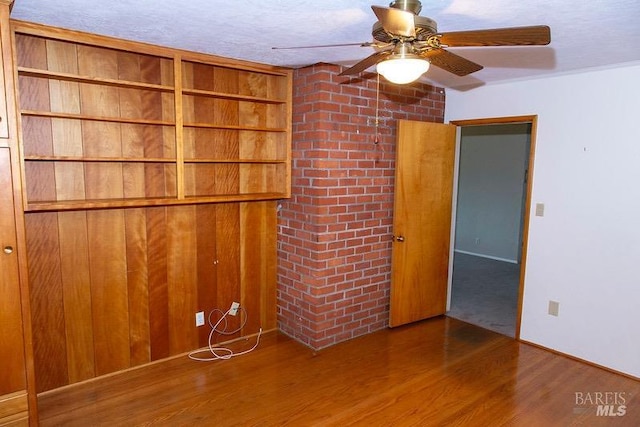 spare room featuring brick wall, a textured ceiling, hardwood / wood-style flooring, and ceiling fan