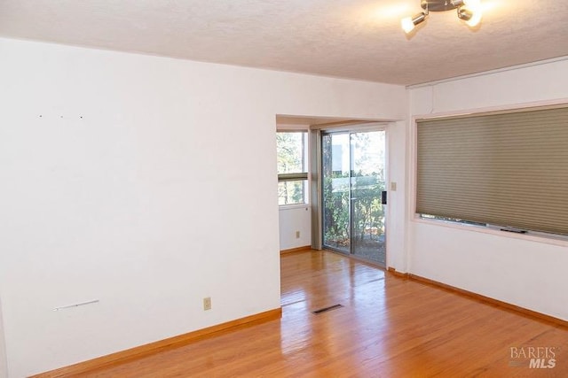 unfurnished room with a textured ceiling and hardwood / wood-style floors