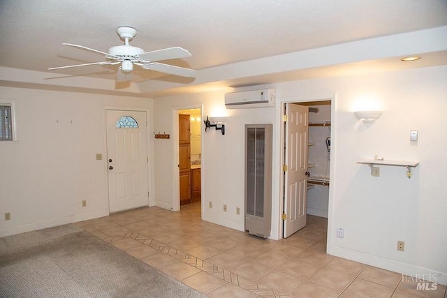 tiled spare room featuring an AC wall unit, a tray ceiling, and ceiling fan