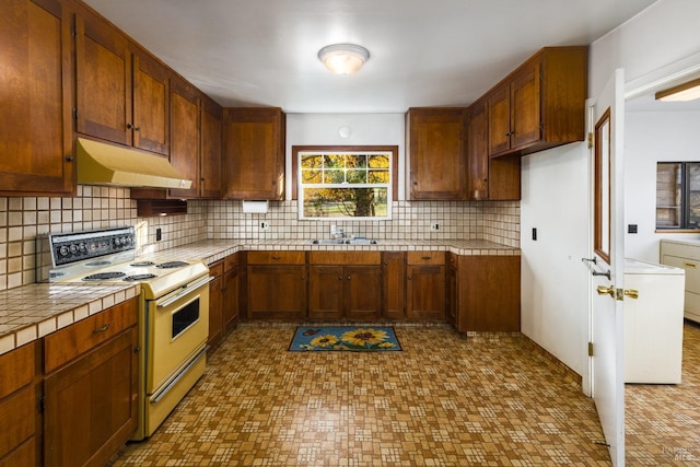 kitchen featuring custom exhaust hood, tasteful backsplash, white electric range oven, and tile patterned floors