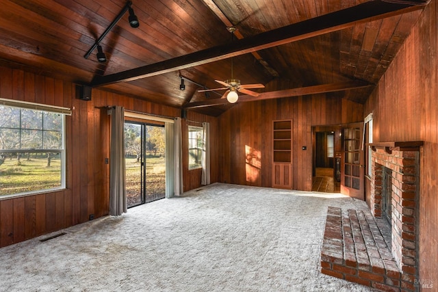 unfurnished living room featuring vaulted ceiling with beams, wood ceiling, wooden walls, rail lighting, and a fireplace