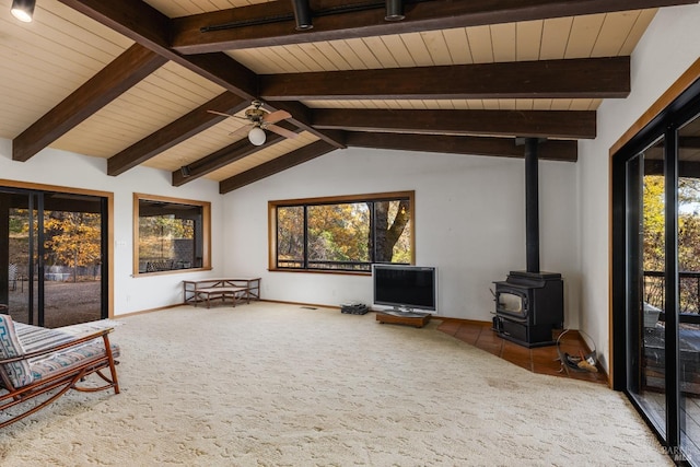 sitting room featuring ceiling fan, a wood stove, tile patterned flooring, wooden ceiling, and lofted ceiling with beams