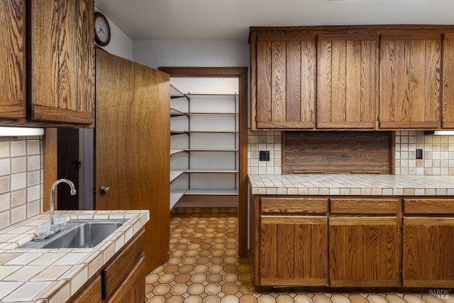 kitchen with sink, decorative backsplash, tile patterned floors, and tile counters