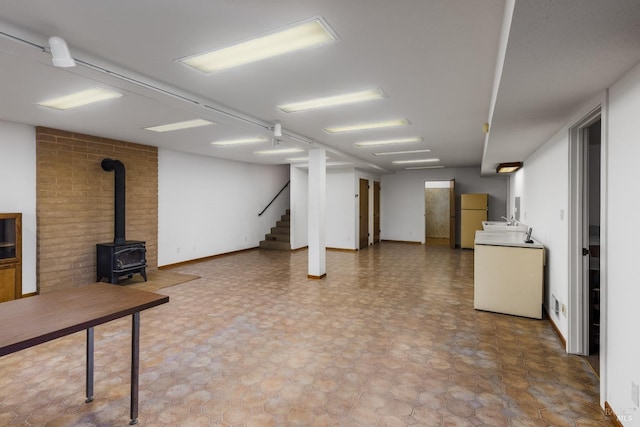 basement with white fridge, a wood stove, and tile patterned floors