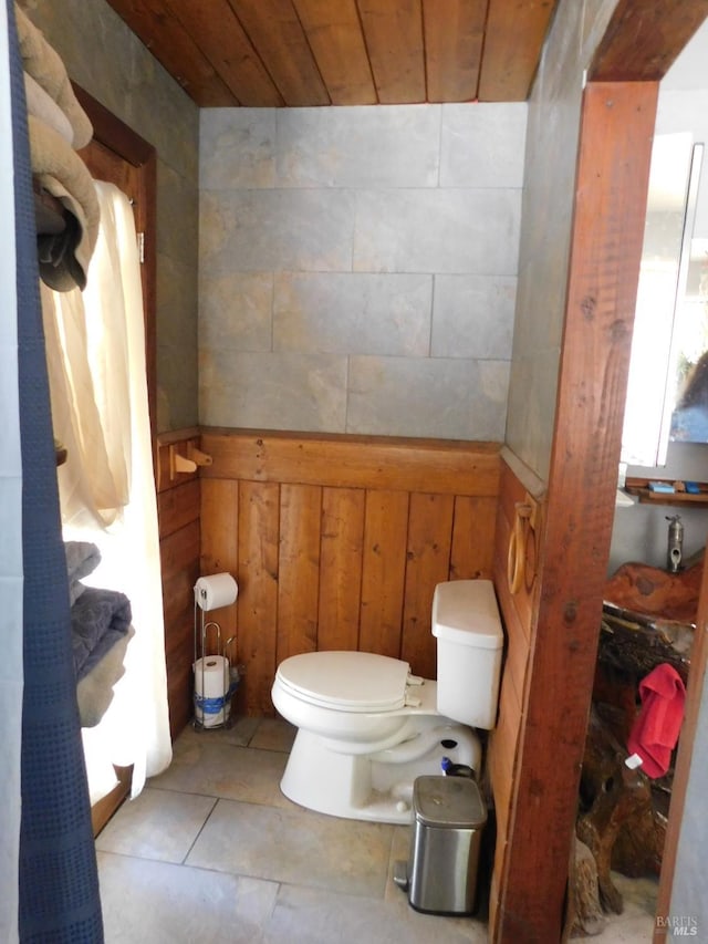 bathroom with tile patterned floors, wooden walls, wood ceiling, and toilet