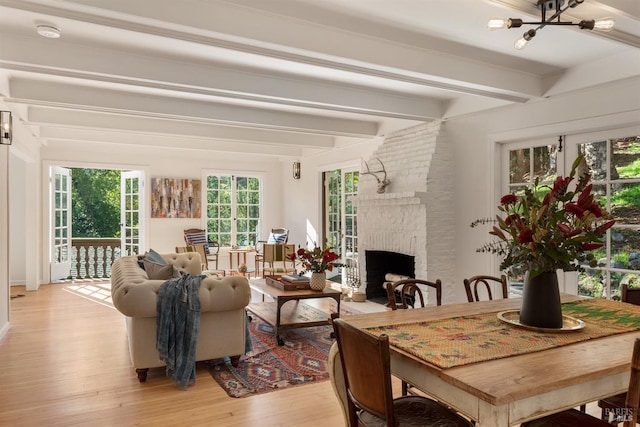 living room featuring brick wall, light wood-type flooring, a brick fireplace, and beam ceiling