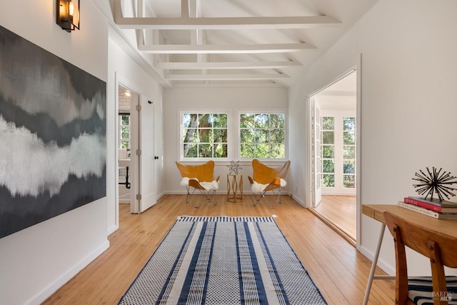 living area with vaulted ceiling with beams and light hardwood / wood-style flooring