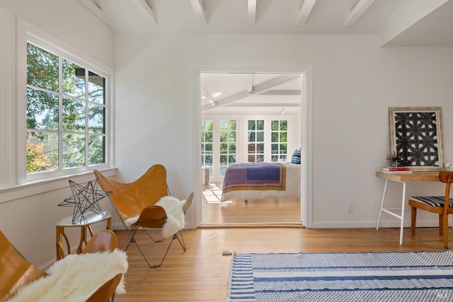 sitting room with beamed ceiling, hardwood / wood-style flooring, and plenty of natural light