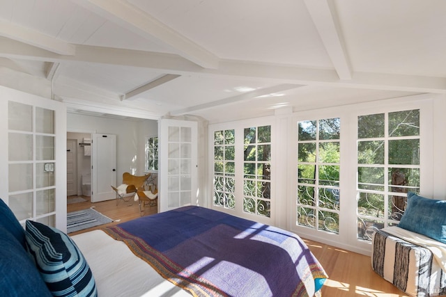 bedroom with lofted ceiling with beams, french doors, and light hardwood / wood-style flooring