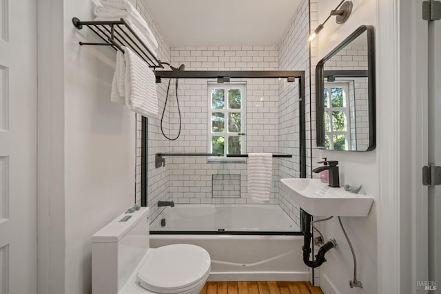 full bathroom with plenty of natural light, enclosed tub / shower combo, wood-type flooring, and toilet