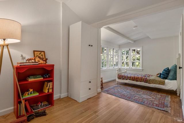 bedroom with vaulted ceiling with beams and hardwood / wood-style floors