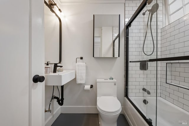 bathroom with toilet and shower / bath combination with glass door