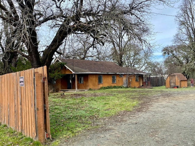 single story home with a storage shed and a front lawn