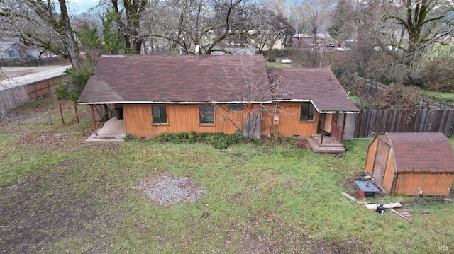 rear view of property with a storage shed and a yard